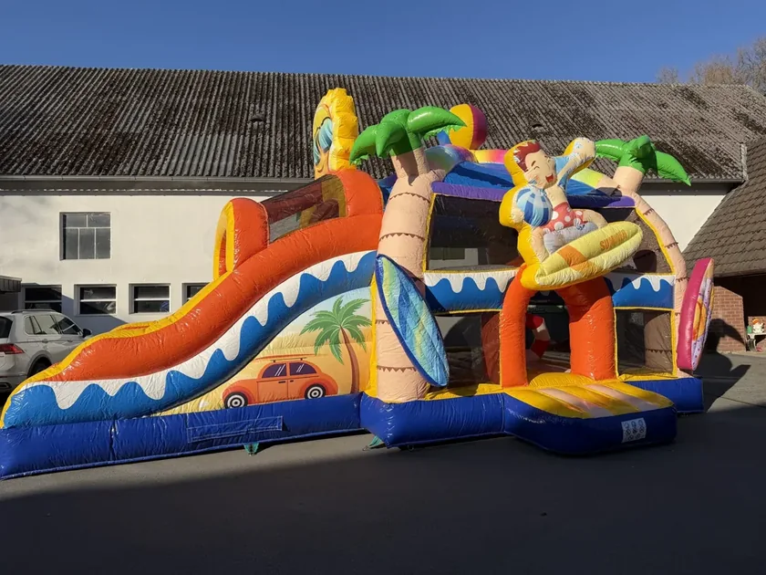 Originalaufnahme der Hüpfburg Holiday Island mit Rutsche und Palmenmotiven.
